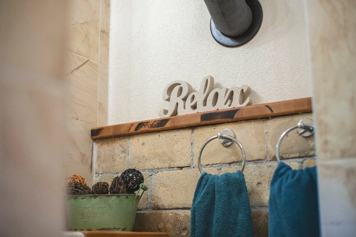 Detail kúpeľne s nápisom Relax a tehlovou stenou